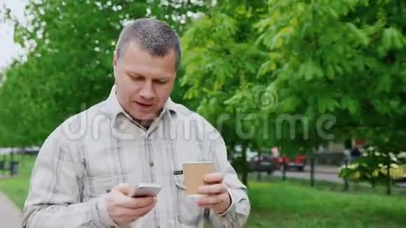 中年男子一边喝咖啡一边走在城市公园视频的预览图