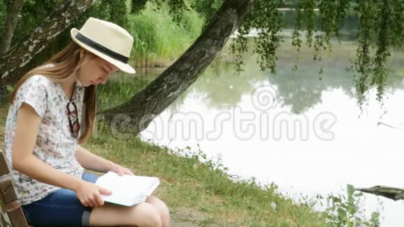 一个小女孩在湖边的长凳上看书视频的预览图