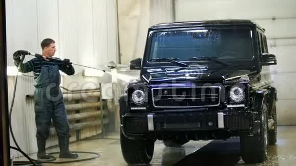 汽车服务部门的工人正在用水管冲洗一辆豪华轿车背光视频的预览图