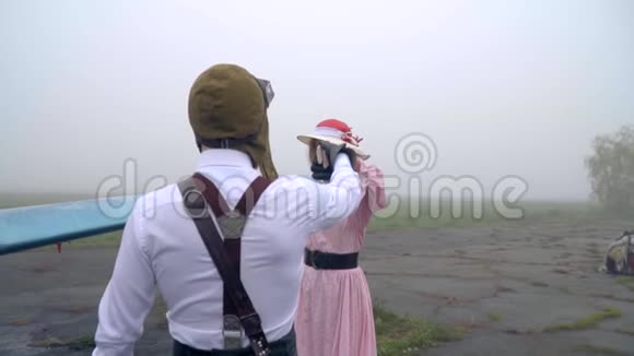 一个穿着粉红色裙子的女人正在飞机前和飞行员跳舞动作缓慢视频的预览图