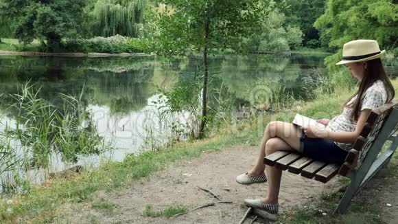一个小女孩在湖边的长凳上看书视频的预览图