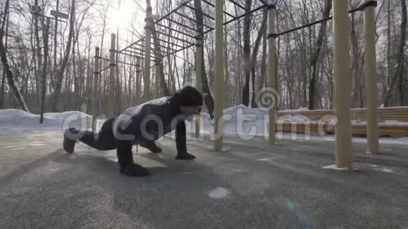 强壮的男子在冬季运动场上训练俯卧撑视频的预览图