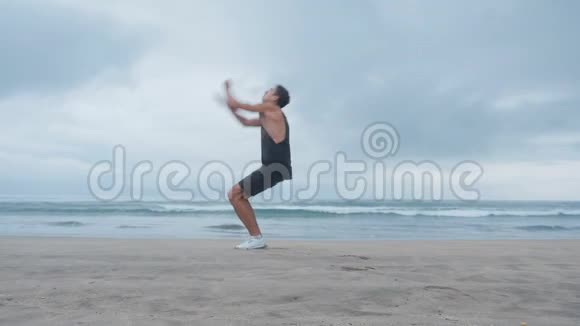 年轻人在海滩上做交叉训练他在海滩的背景下按下并做了一个后翻视频的预览图