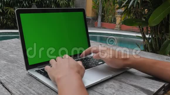 人在笔记本电脑绿屏工作室外整洁的游泳池工作和休闲视频的预览图