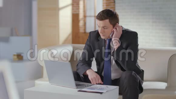 帅哥商务套装完成电话工作笔记本电脑视频的预览图
