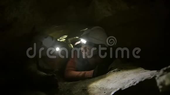 两个年轻的徒步旅行者探险者困在黑暗洞穴的窄洞里视频的预览图