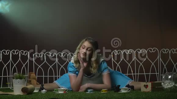 爱丽丝拿着茶具坐在草地上视频的预览图