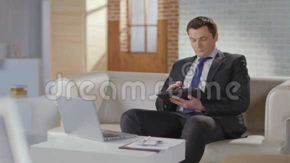 穿着考究的商人在办公室的平板电脑上搜索滚动视频的预览图