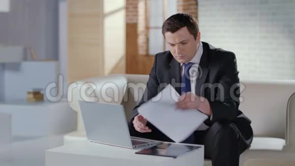 商人在办公室检查文件在笔记本电脑上举行网络会议视频的预览图