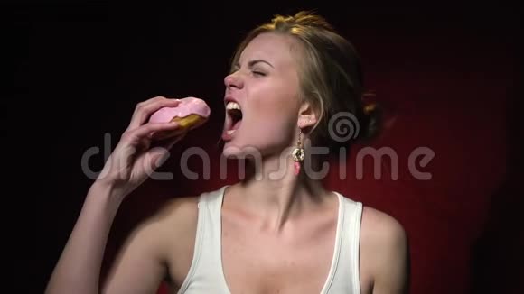 金发女郎正要咬掉甜甜圈但她改变了主意慢慢地靠在脸颊上视频的预览图