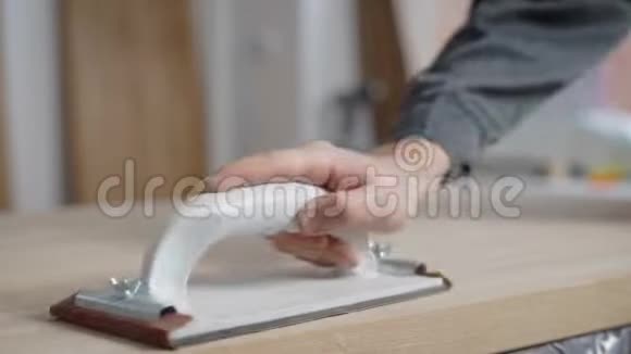 一位专业木匠在车间用砂纸打磨一块木板视频的预览图