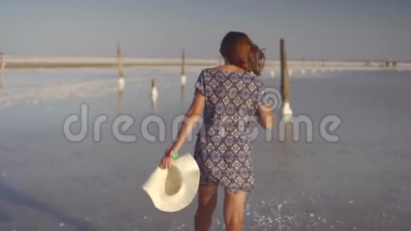 苗条的女孩享受日落轻轻地走在盐湖的水上视频的预览图