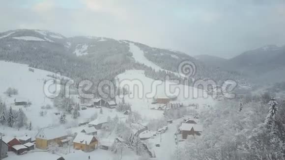 飞越喀尔巴阡山的一个村庄鸟山上白雪覆盖的房子的视野乡村景观视频的预览图