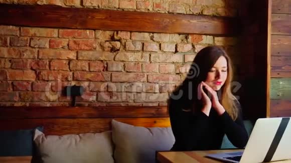 幸福的女人在砖墙附近的咖啡馆通过笔记本电脑在网上赢得赌注视频的预览图