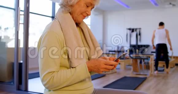 4k瑜伽中心使用手机的老年妇女视频的预览图