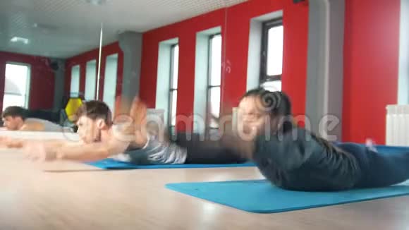 在健身课上男女青年在地毯上锻炼视频的预览图