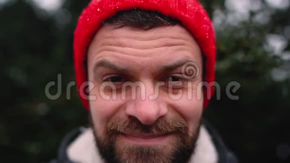 一个戴红帽子的男人在户外下雪时的肖像视频的预览图