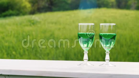 两杯绿柠檬水放在春天花园的绿色草坪的背景上春季和圣帕特里克节概念视频的预览图