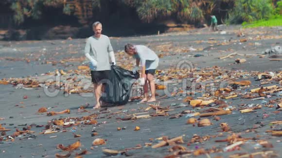 群志愿者清理沙滩志愿者举起并把一个塑料垃圾扔进袋子里环境视频的预览图
