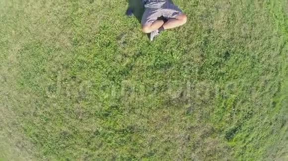 快乐的人躺在草地上头后的手空中射击视频的预览图