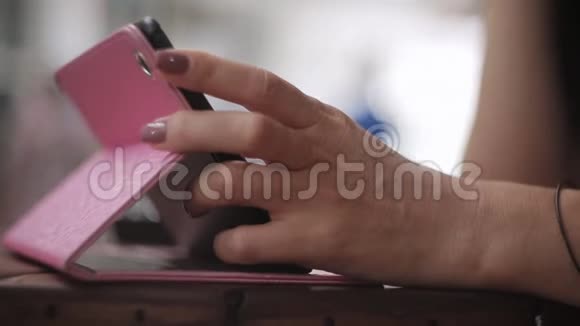 年轻女孩坐在餐桌旁的咖啡馆里用平板电脑双手特写视频的预览图
