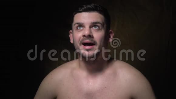 一个留着胡子的黑发男子站在一个黑暗的背景上高兴视频的预览图