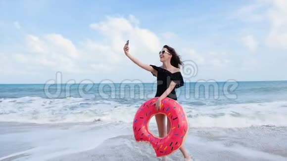 迷人的年轻女子与甜甜圈浮动玩得开心和享受暑假在热带海滩度假放松的女人视频的预览图