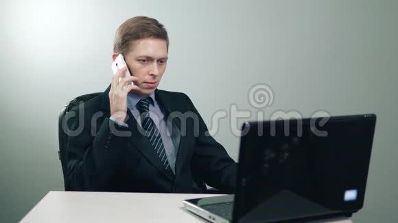 穿着西装的商人在办公室的笔记本电脑前打电话视频的预览图