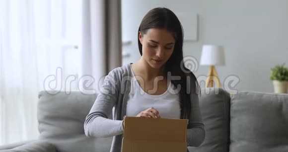 满意女顾客打开包裹盒坐在沙发上视频的预览图