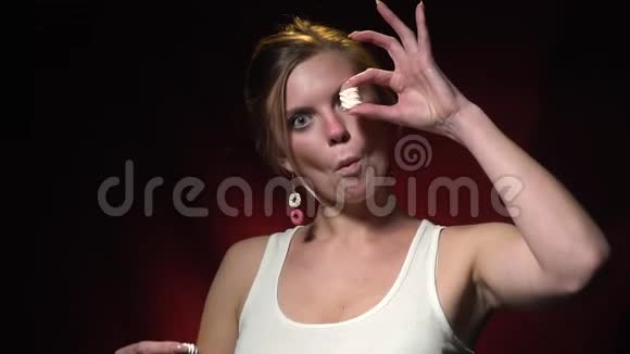 一个活泼开朗的金发女人在用棉花糖代替眼睛然后吃它们时做鬼脸视频的预览图