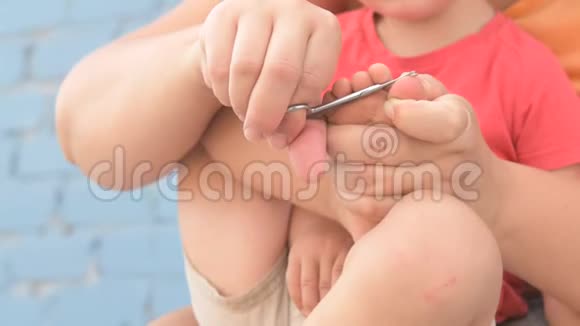 女妈妈正在给一个年幼的孩子剪指甲视频的预览图