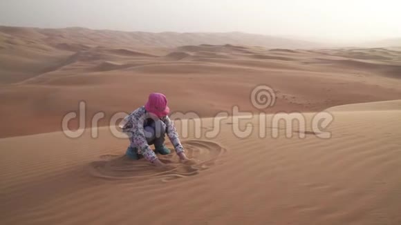 少年女孩在RubalKhali沙漠中的沙滩上作画视频的预览图