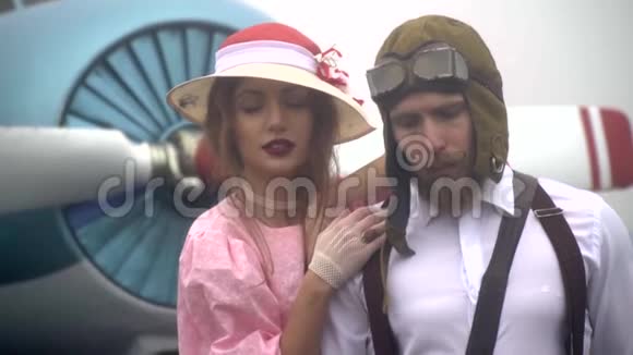 一对相爱的夫妇一个穿着连衣裙的女人拥抱着一个留胡子的男飞行员的肩膀慢动作视频的预览图