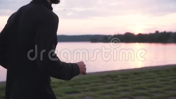 慢动作运动员享受健康的生活方式年轻的自由男运动员在宁静的日落湖跑步侧视视频的预览图