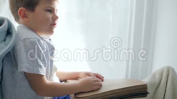 盲人和有视力障碍的儿童在窗台上阅读盲文书的教育视频的预览图