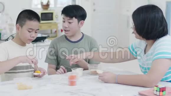 快乐的亚洲孩子喜欢在家里微笑着吃饭视频的预览图