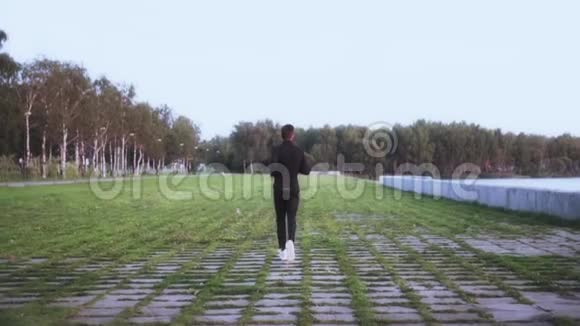 慢动作运动员享受健康的生活方式背景镜头年轻人在草地上奔跑从远处看视频的预览图