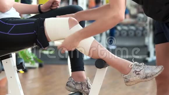 在健身房用绷带包扎女孩的腿视频的预览图