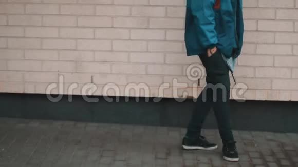 穿着时髦衣服的年轻人走在砖墙前面视频的预览图