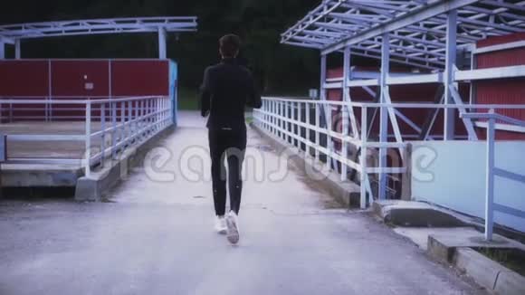 慢动作适合运动员在小桥上跑步背景镜头健身在郊区景观中运行后景视频的预览图