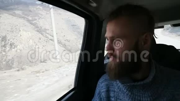 一个会说话的留着胡须的嬉皮士男性坐在车后座两边沉思的特写照片视频的预览图