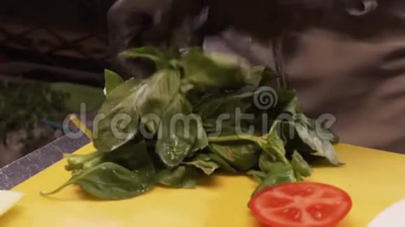 厨师的手撕下新鲜罗勒的叶子视频的预览图