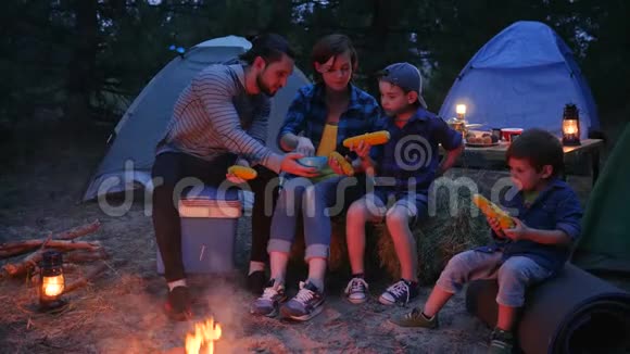 一家人在外面吃玉米在森林里露营野餐妈妈爸爸和儿子晚上吃新鲜的黄色玉米视频的预览图