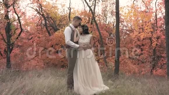 一对相爱的夫妇在秋树之间有点慢动作视频的预览图