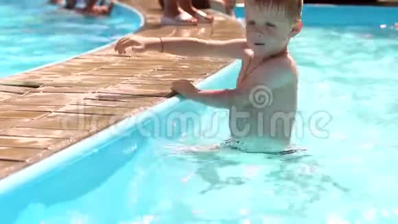 一个有趣的金发男孩在夏天在游泳池里玩和游泳视频的预览图
