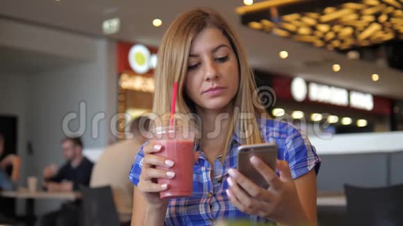 年轻漂亮的女人用智能手机从地铁到咖啡馆喝果汁视频的预览图
