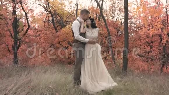 一对恋爱中的漂亮夫妇站在秋树中间互相压着视频的预览图