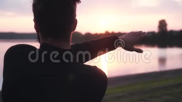 慢动作自由人锻炼日出湖在美丽的晨水全景中男性摆动手臂的后景视频的预览图