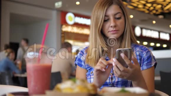 年轻漂亮的女人用智能手机从地铁到咖啡馆喝果汁视频的预览图