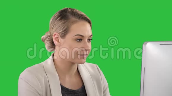 成年女商人在办公室里用绿色屏幕看电脑彩色钥匙视频的预览图